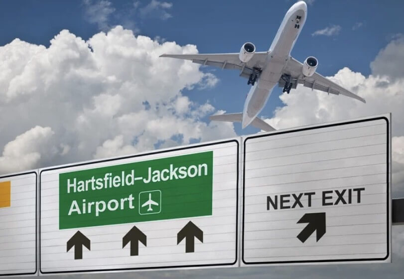Airplane flying over Hartsfield-Jackson Atlanta Airport road sign, ideal for service airport transportation.
