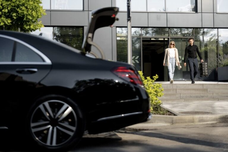 swn - KLEO Black Car Service Suwanee limo service with luxury black car and professional chauffeur picking up passengers at office building.